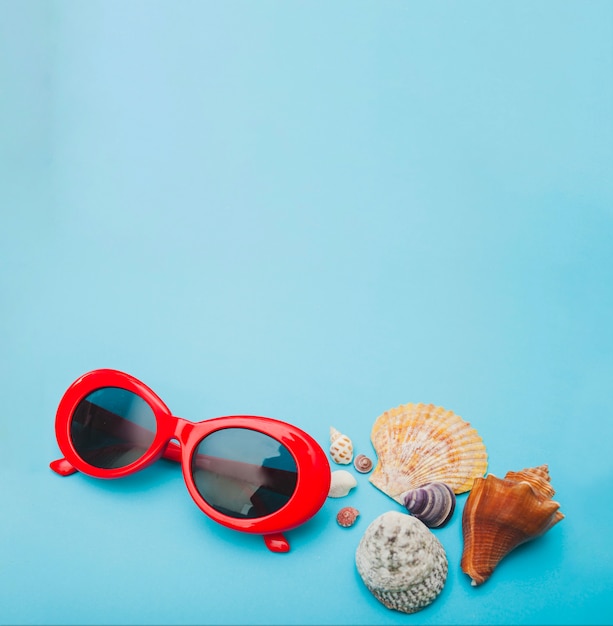 Blue surface with red sunglasses and seashells