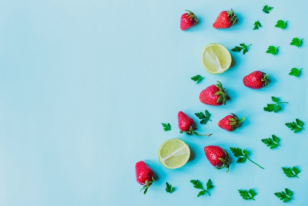 Free photo blue surface with strawberries and limes