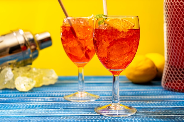 민트와 오렌지 잎을 곁들인 상쾌한 아페롤 스프리츠 칵테일 2잔이 있는 파란색 테이블