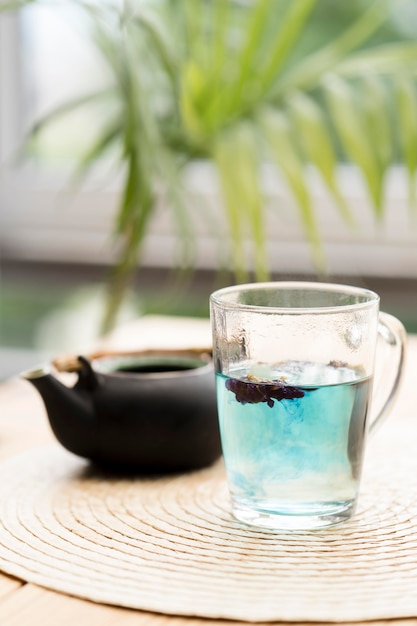 Blue tea in glass near teapot
