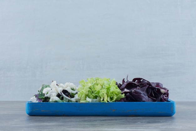 Free photo blue tray of chopped cabbage, cauliflower and amaranth on marble.