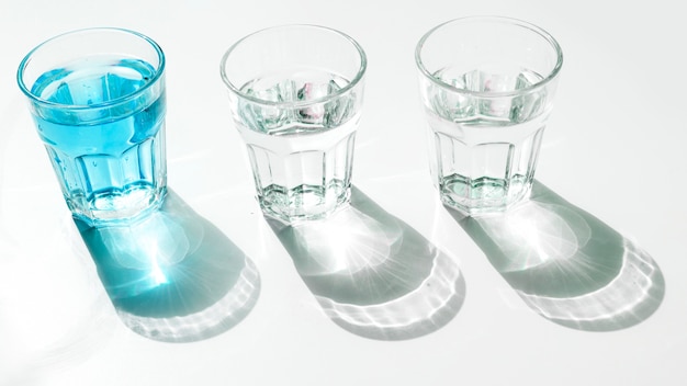 Blue water glasses with shadow on white backdrop