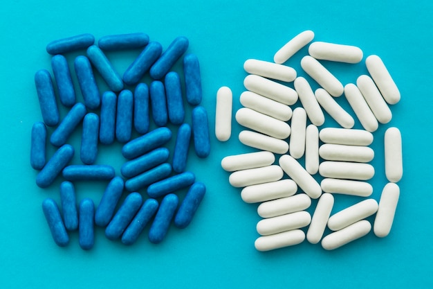 Blue and white candy capsules on cyan backdrop