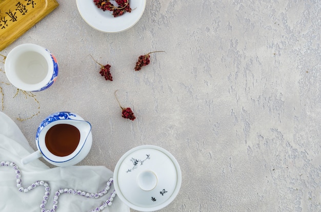 Set da tè in porcellana cinese blu e bianca con erbe su sfondo grigio cemento