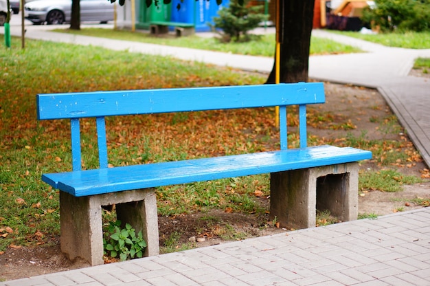秋の公園の青い木製のベンチ