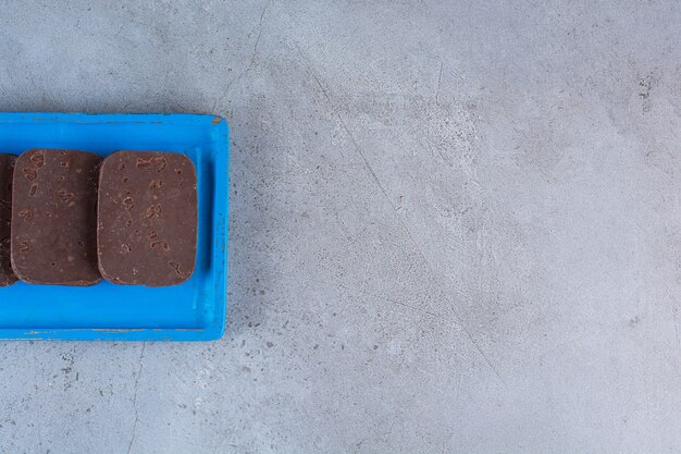 A blue wooden board of chocolate cookies on gray