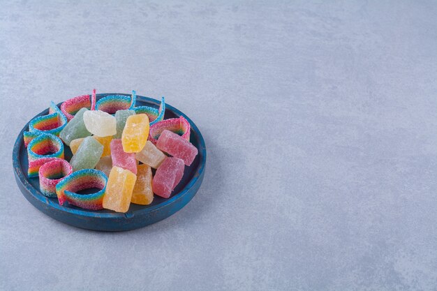 A blue wooden board full of colorful sugary marmalades 