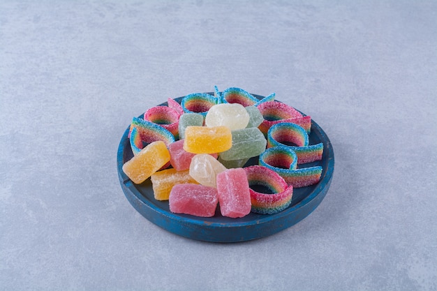 A blue wooden board full of colorful sugary marmalades 