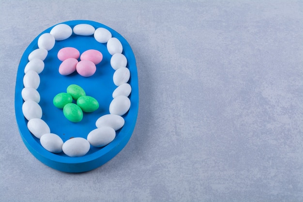 A blue wooden board full of colorful sweet jelly bean candies . 