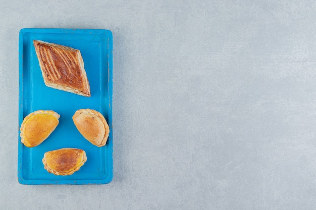 A blue wooden board full of sweet cookies .  