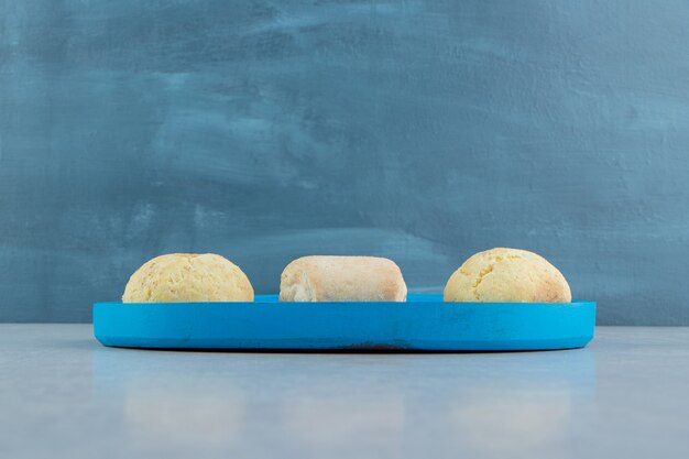 A blue wooden board full of sweet cookies . 