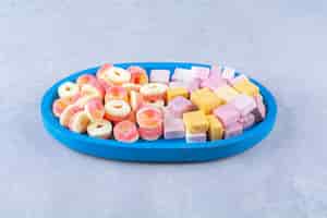 Free photo a blue wooden board of sugary red jelly candies with sweet rainbow liquorice . high quality photo