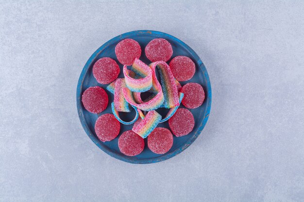 Free photo a blue wooden board of sugary red jelly candies with sweet rainbow liquorice .