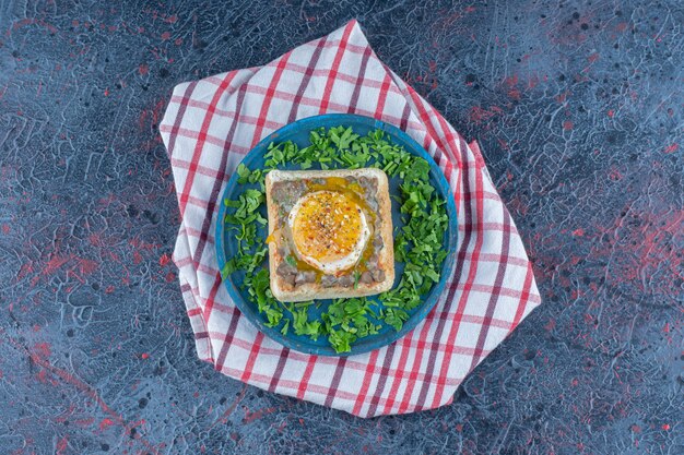 A blue wooden board of toast with egg and herbs. 