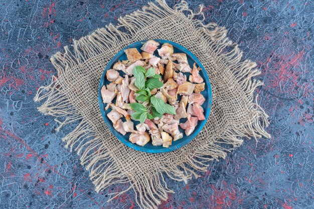 Free photo a blue wooden board with slice chicken meat and mint.