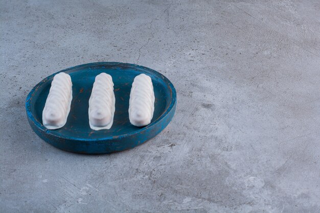 A blue wooden board with three sweet white sticks .