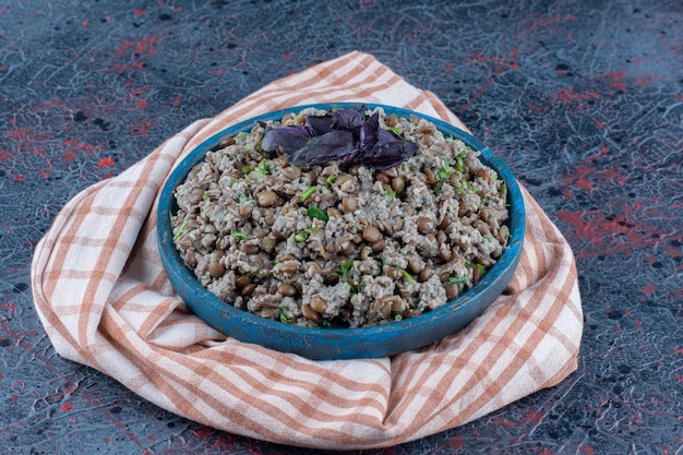 A blue wooden plate of mincemeat with peas and herbs 