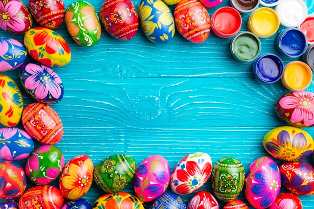 Blue wooden surface with easter eggs and paint jars