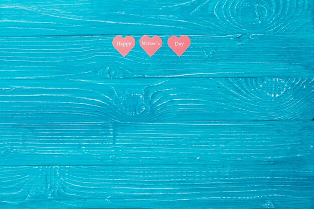 Blue wooden surface with three paper hearts and blank space