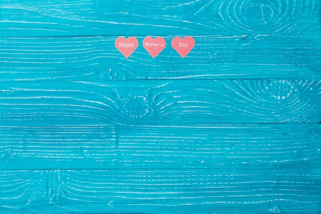 Blue wooden surface with three paper hearts and blank space