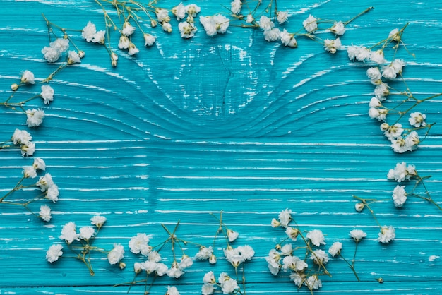 Free photo blue wooden table with frame made of flowers