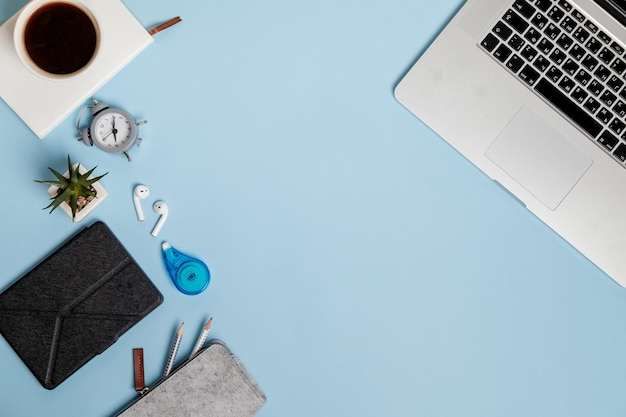 Luogo di lavoro blu con laptop e tazza di caffè vista dall'alto disposizione piatta