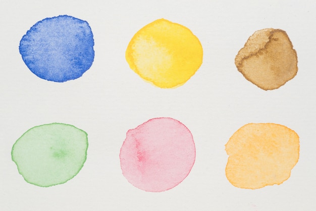 Free photo blue, yellow, brown, green, pink and orange paints on white paper