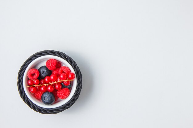 Blueberries and raspberries in a bowl with redcurrant top view