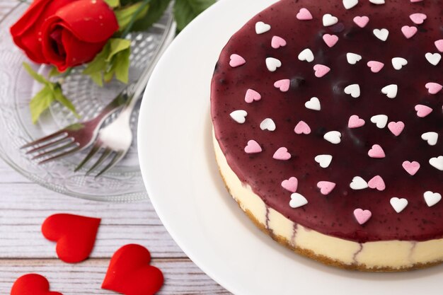 Foto gratuita cheesecake ai mirtilli decorata con cuori dolci sulla tavola di legno