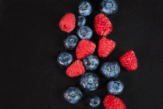 Blueberry and raspberry isolated on black background. Raw berries mix isolated.