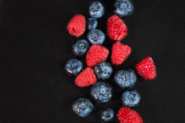 Blueberry and raspberry isolated on black background. Raw berries mix isolated.