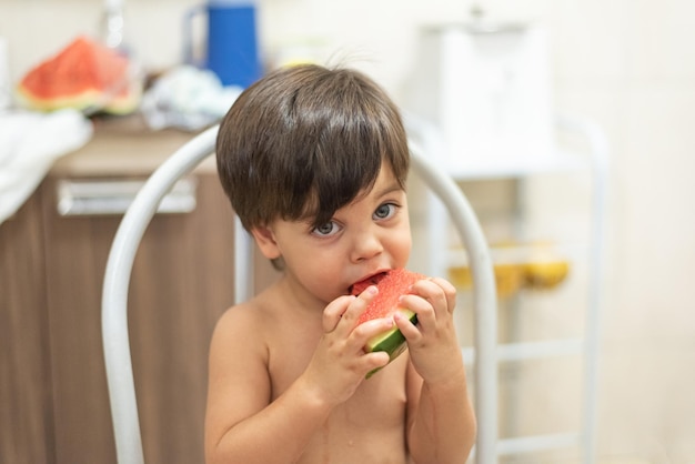 Blueeyed baby boy eating watermelon