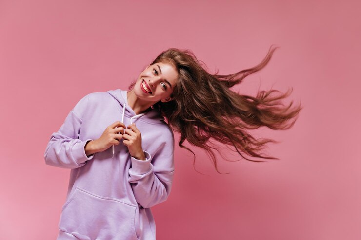 Free Photo blueeyed young woman in purple oversized hoodie plays wavy hair goodhumored girl in light sporty outfit poses on pink background with smile