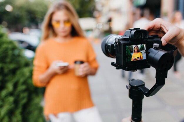 Blur portrait of woman in yellow glasses with black camera in focus