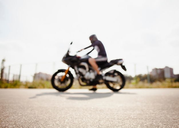 Foto gratuita motociclista offuscata parcheggiato sulla strada