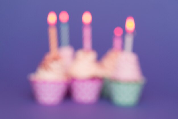 Blurred birthday cupcakes with lit candles