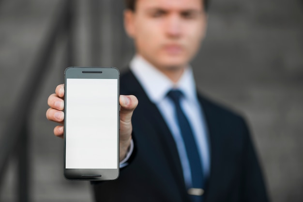Бесплатное фото Размытый бизнесмен, показывая смартфон