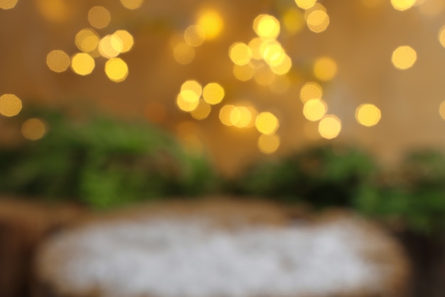 Blurred christmas background with bright defocus bokeh lights and a wooden surface with snow