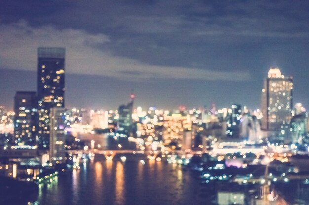 Blurred city with skyscrapers and a river at night