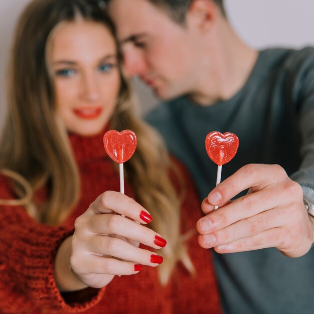 Blurred couple showing heart lollipops