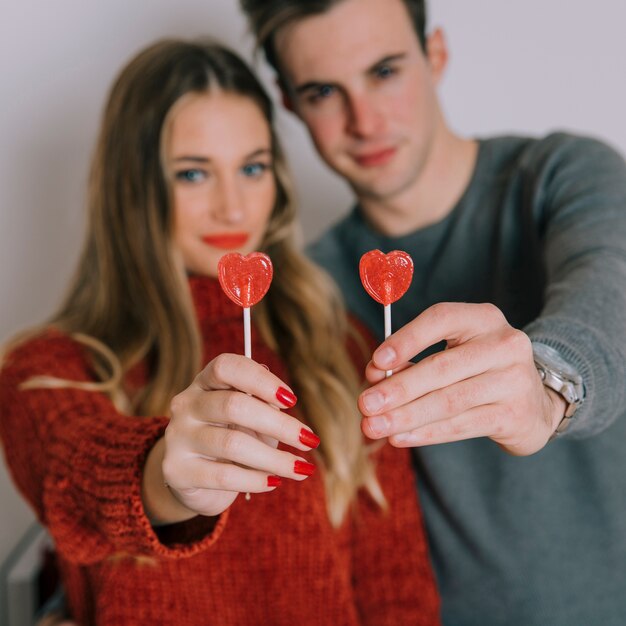 Blurred couple with heart lollipops