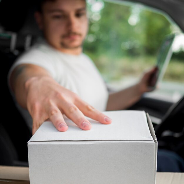 Blurred delivery man in car touching box