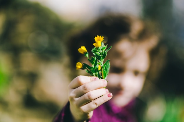 Foto gratuita ragazza vaga che mostra i fiori selvaggi