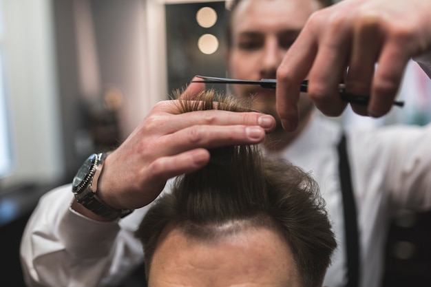 Blurred hairdresser cutting hair of customer