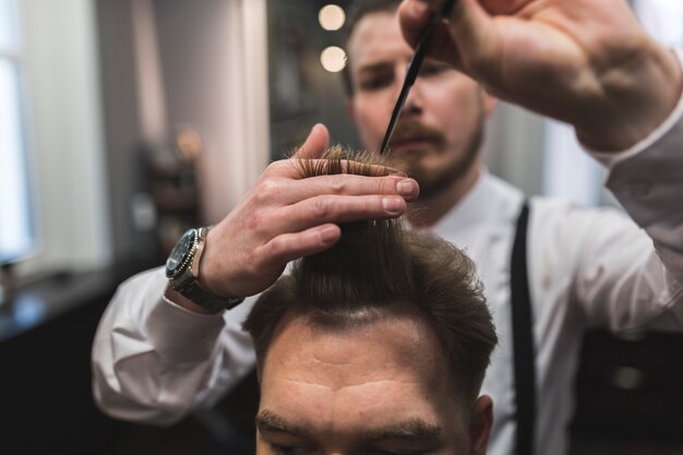 Blurred hairdresser cutting hair of male client