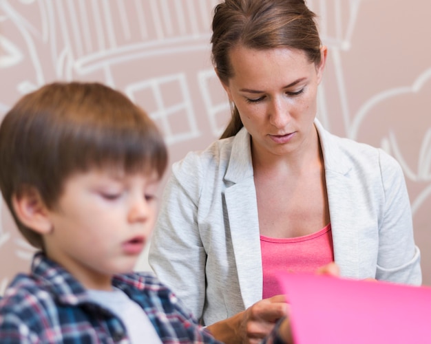 Bambino sfocato e insegnante con carta colorata