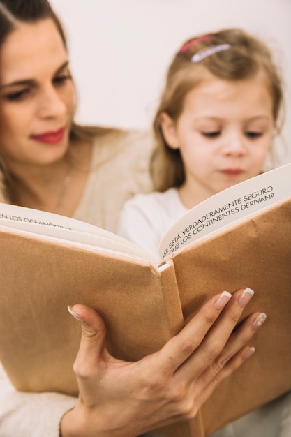 Free photo blurred mother and daughter reading book