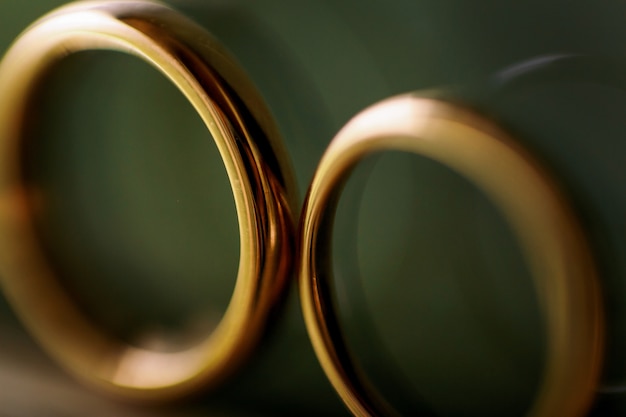 녹색 배경에 서있는 결혼 반지의 흐릿한 사진