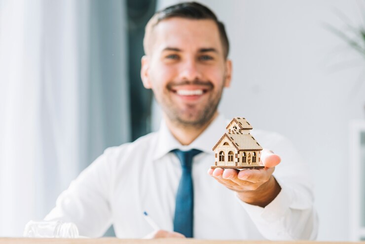 Blurred real estate agent holding toy house