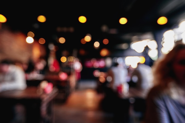 Blurred restaurant or cafe background. Tables and chairs in the lobby of the mall. Visitors to the restaurant for dinner. Beautiful bright interior. Blurred bokeh basic background for design